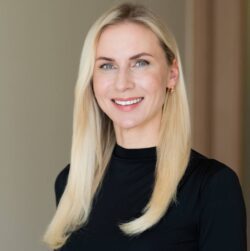 Portrait de Marta Slaidina, PDG et Directrice Médicale de la Clinique EGV, portant un haut noir et ayant de longs cheveux blonds.