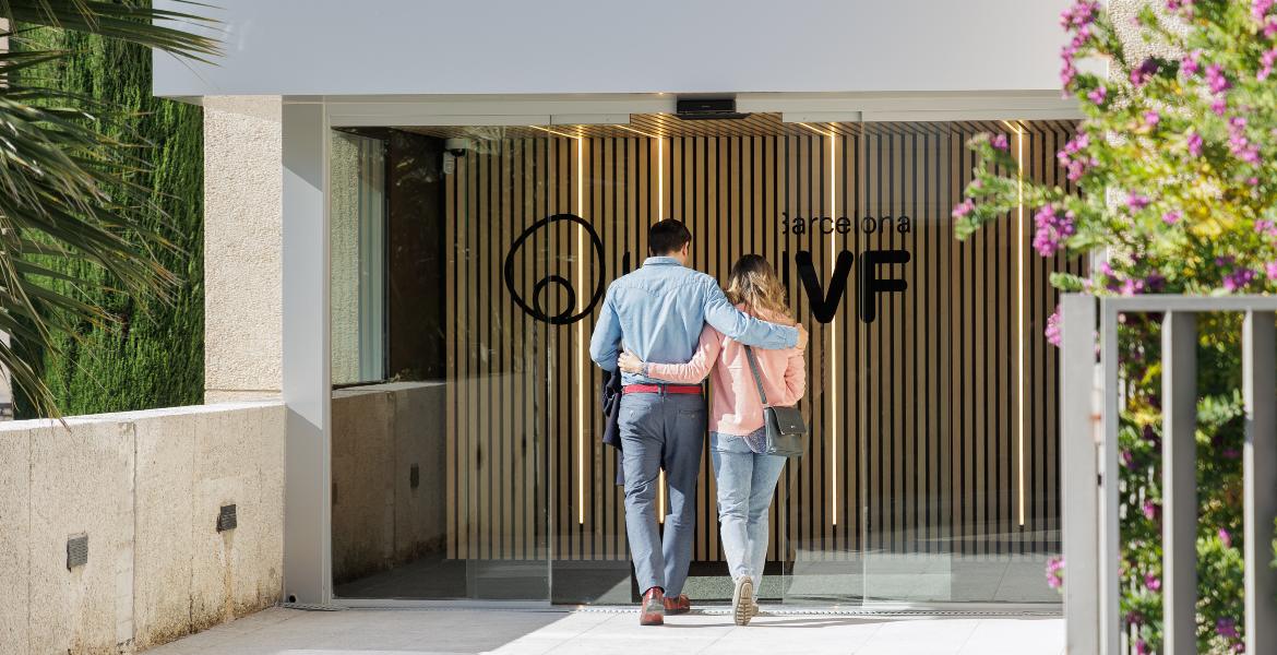 Un couple entre ensemble dans la clinique Barcelona IVF, l’un tenant l’autre par la taille, symbolisant le début d’une prise en charge pour un traitement de fertilité.