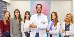 Drakopoulos Reproductive Medicine team in Athens, with lead fertility doctor and five female specialists standing together in the clinic in front of a pink artwork.