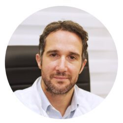 Photo de profil d'un spécialiste de la FIV à la clinique de médecine reproductive Drakopoulos, montrant un médecin en blouse blanche assis sur une chaise de bureau, le visage flouté pour des raisons de confidentialité.